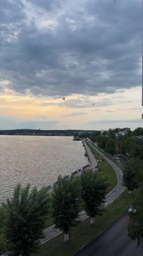 Birds fly over Votkinsk Reservoir waterfront during cloudy afternoon