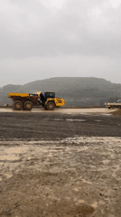 Yellow dump truck operates in German quarry during cloudy morning