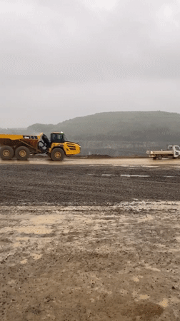 Yellow dump truck operates in German quarry during cloudy morning