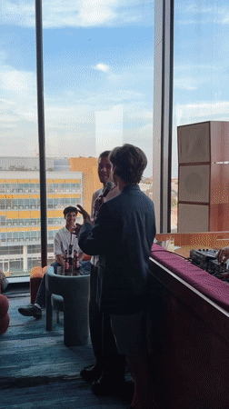 Indoor gathering in London with people mingling and speaking on mic