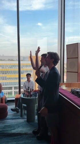Indoor gathering in London with people mingling and speaking on mic
