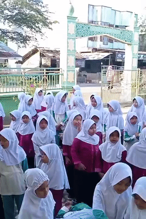 Students gather in Indonesian schoolyard amid blooming desert flowers