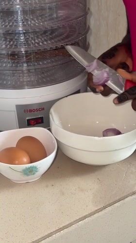 Henna-decorated cook prepares meal, displays clothing in Ado Nigeria