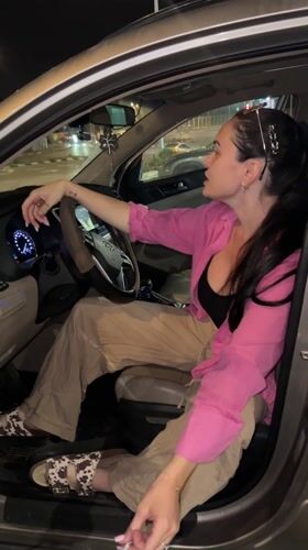 Two women sing together in car at night