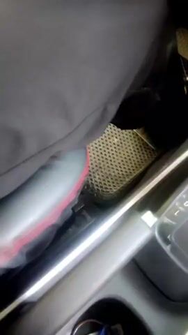 The video shows the interior of a car, focusing on the gear shifter, climate control knobs, and pedals. A person's leg is visible, operating the pedals, and a shoe is seen pressing down on one of the pedals. The gear shifter is in the "P" (Park) position. The climate control panel has three rotary knobs and hazard light button. The steering wheel is also partially visible. The overall impression is that the car is stationary, possibly with the engine running, and the driver is preparing to change gears or has just arrived at their destination.