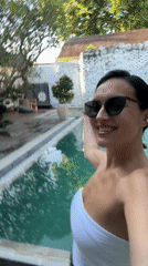 Woman films selfie videos while dancing poolside in North Kuta