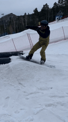Snowboarders perform tricks over obstacles at ski resort