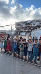 Children peer through metal fence in Gaza