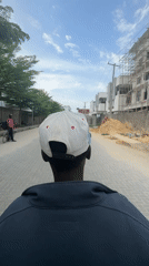 Person in baseball cap walks down brick street in Nigeria