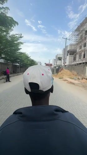 Person in baseball cap walks down brick street in Nigeria