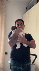 Father tends to baby in bedroom, Aprilia Italy