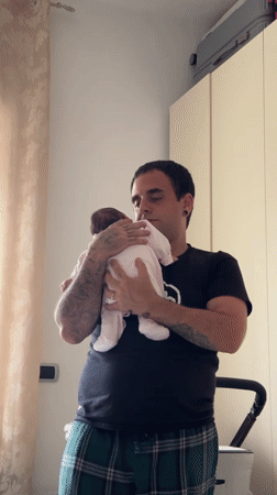 Father tends to baby in bedroom, Aprilia Italy
