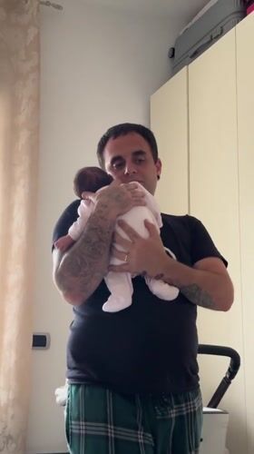 Father tends to baby in bedroom, Aprilia Italy