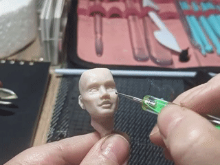 Artist sculpts clay human head with specialized tools