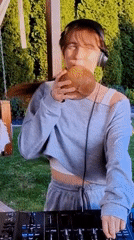 Woman DJs outdoors with mixing board, coconut present