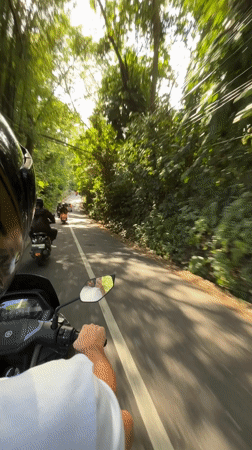 Morning motorcycle commute captured on tree-lined road in Kediri