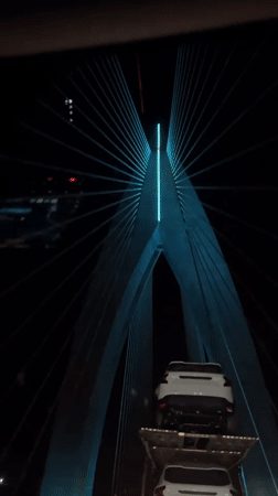 Car carrier crosses illuminated bridge in Morocco at night