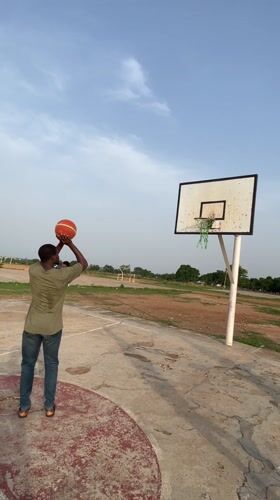 Men play basketball on outdoor court in Akwanga, Nigeria