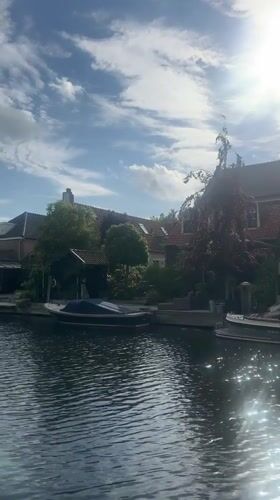 Spring flowers bloom along sunny Katwijk canal with boats