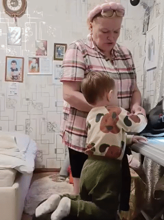 Grandmother and toddler share sewing time in Russian village