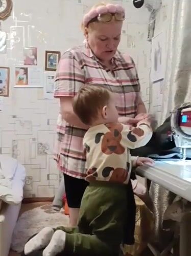 Grandmother and toddler share sewing time in Russian village