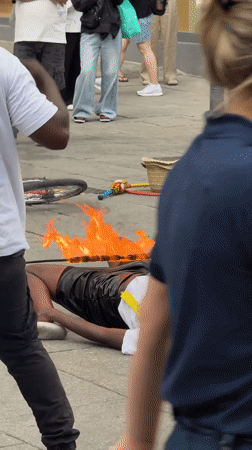 Fire performer balances flaming object on body in Oslo street