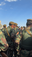 Military formation at a Dushanbe monument, rifles in hand.