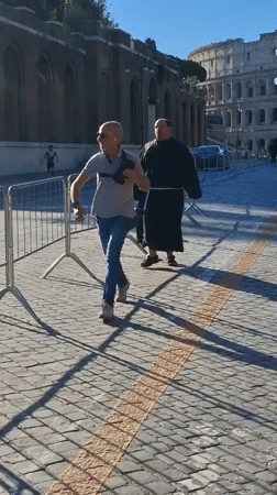 Man and monk walk together near Rome's Colosseum