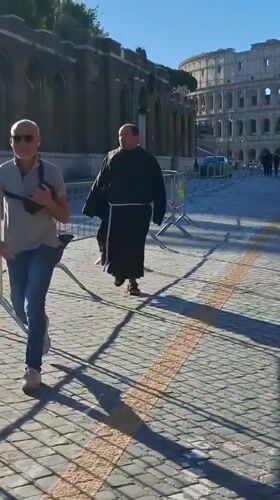 Man and monk walk together near Rome's Colosseum