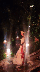Fire dancer performs torch routine on decorated pathway in Blahbatuh