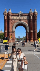 Tourists photograph Barcelona's Arc de Triomf on sunny afternoon