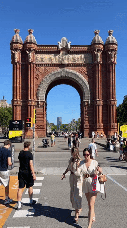 Tourists photograph Barcelona's Arc de Triomf on sunny afternoon