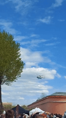 Helicopter circles outdoor family event with archery, carousel activities