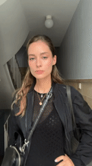 Woman photographed in Kiel stairwell adjusting hair, posing