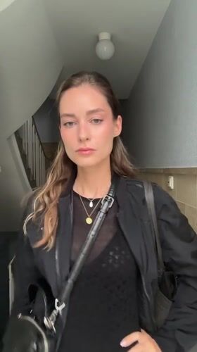 Woman photographed in Kiel stairwell adjusting hair, posing