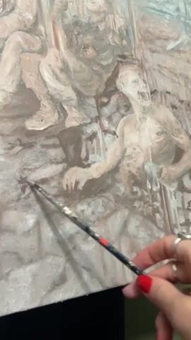 A hand with red painted nails holds a brush and touches an oil painting on canvas. The painting features many figures in tones of beige, white, gray, and brown. The figures appear to be human but have a distressed or tormented look to them. The brush touches the bottom left corner of the painting, adding detail to a figure there.  The video is a close-up shot of the hand and the painting.