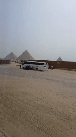 Tourist buses, visitors gather at Great Pyramid under hazy skies