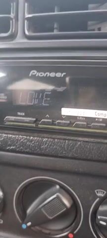 The video shows a close-up of a Pioneer car stereo system. The display screen shows the word "LOVE" in large letters, with some smaller text above and below it. There are also buttons and knobs visible on the stereo. The background is dark and appears to be the interior of a car.