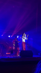 Female singer and guitarist perform under colorful stage lights