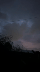 Storm clouds gather over Biysk as goats roam wet ground below