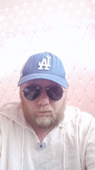 Bearded man in Dodgers cap photographed against string lights