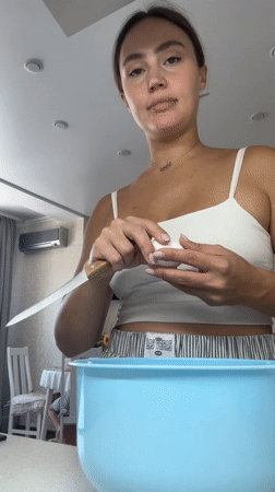 Woman cooks breakfast with baby present in Surgut kitchen