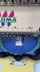 Embroidery machine stitching a white logo onto blue fabric