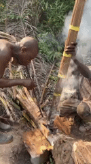 Two men tend fire in Ghana forest