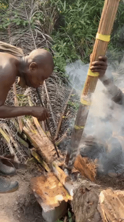 Two men tend fire in Ghana forest