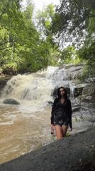 Woman poses at waterfall base in Sri Lankan forest