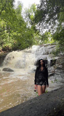 Woman poses at waterfall base in Sri Lankan forest
