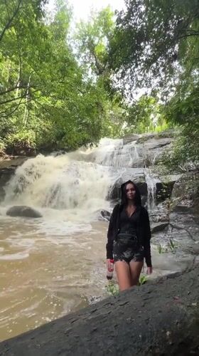 Woman poses at waterfall base in Sri Lankan forest