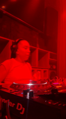 Female DJ performs with Pioneer equipment in red-lit Moscow venue