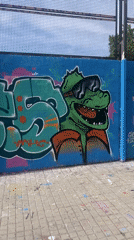 Man plays soccer with dogs near graffiti wall in Barcelona